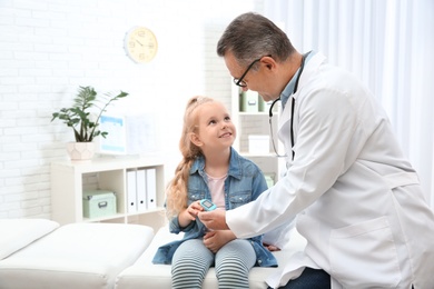 Doctor checking little girl's pulse with medical device in hospital. Space for text