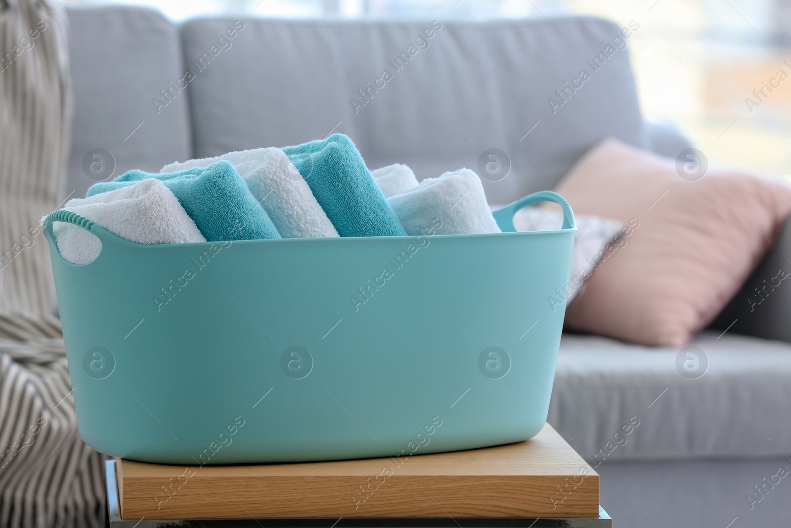 Photo of Laundry basket with clean towels on table indoors