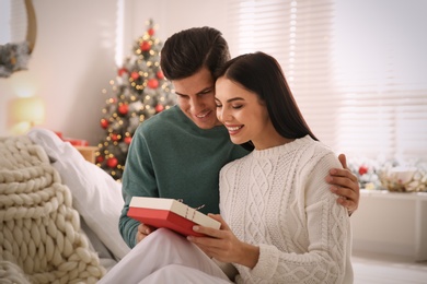 Happy couple with gift at home. Christmas celebration