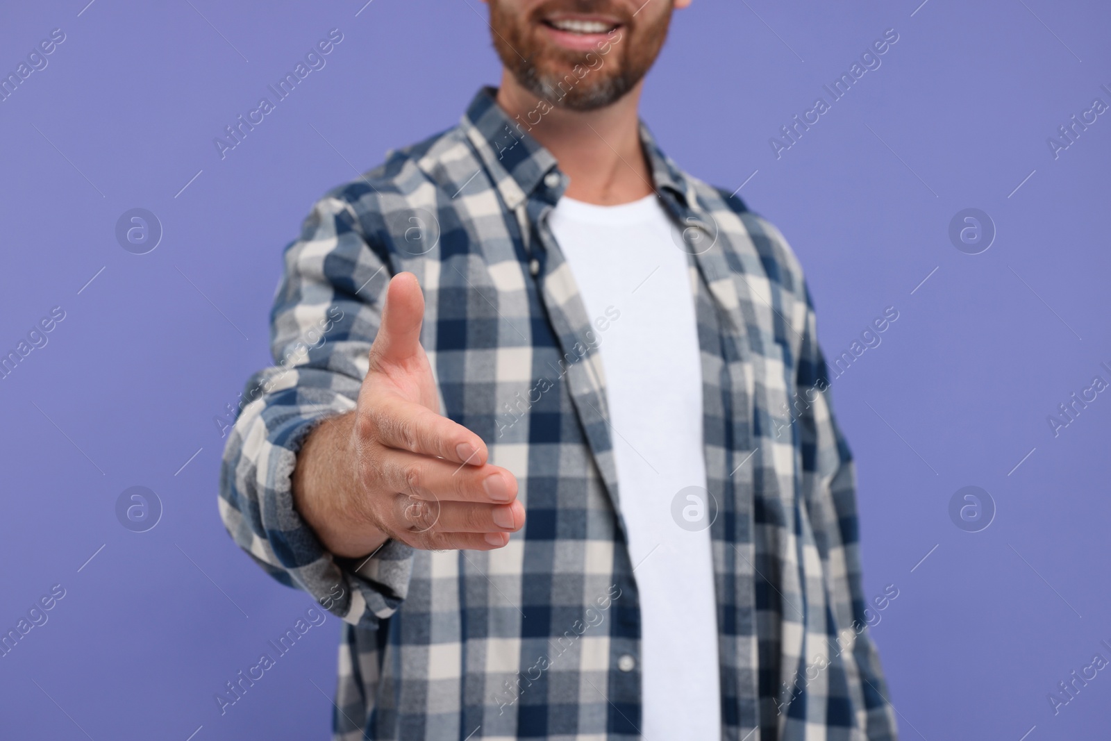 Photo of Man welcoming and offering handshake on purple background, closeup