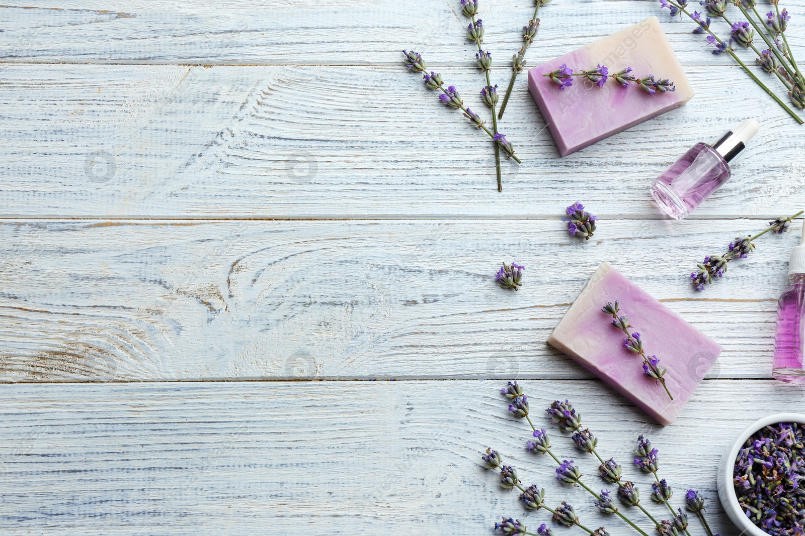 Photo of Flat lay composition of handmade soap bars with lavender flowers on white wooden background. Space for text