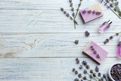 Flat lay composition of handmade soap bars with lavender flowers on white wooden background. Space for text