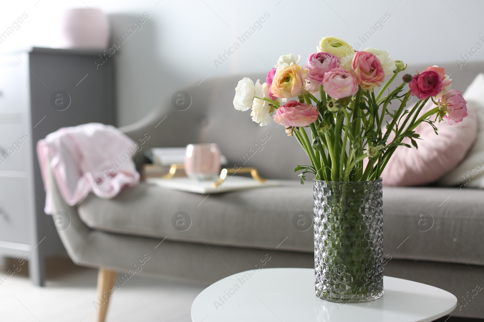 Photo of Bouquet of beautiful ranunculuses on table in living room. Space for text