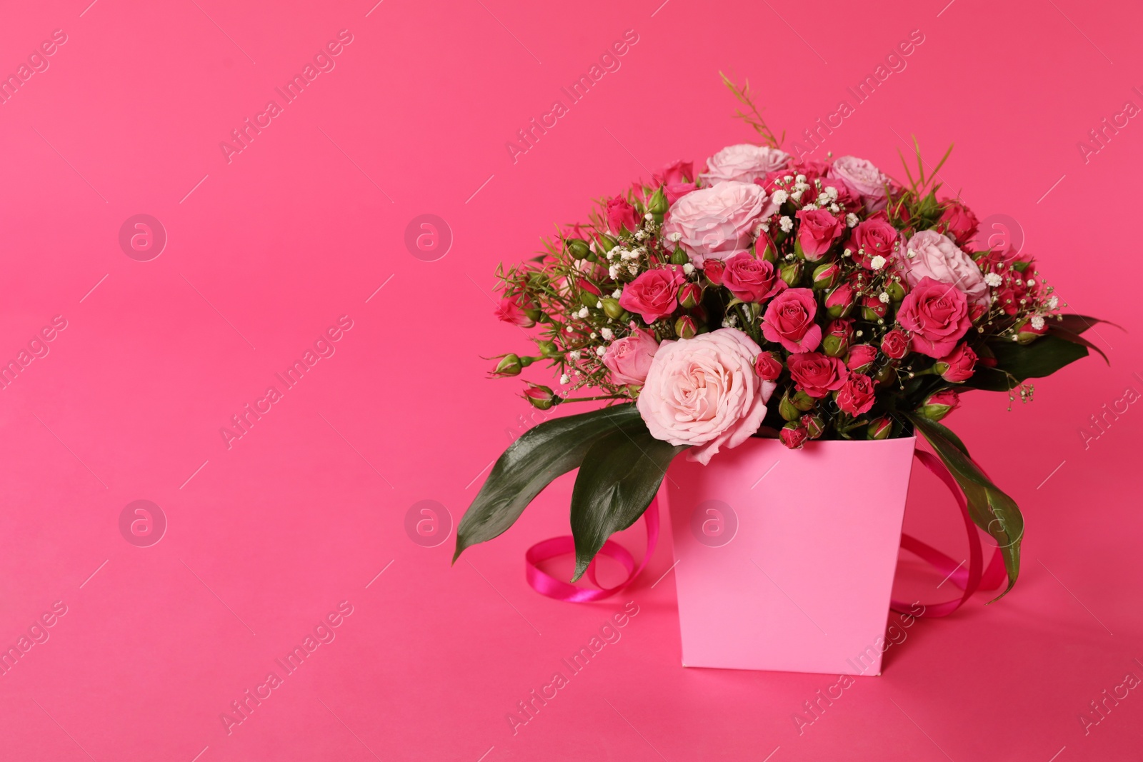 Photo of Beautiful bouquet of flowers in paper gift box on color background. Space for text