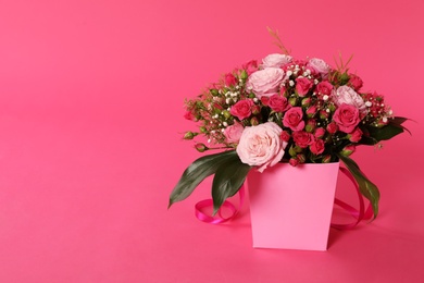 Photo of Beautiful bouquet of flowers in paper gift box on color background. Space for text