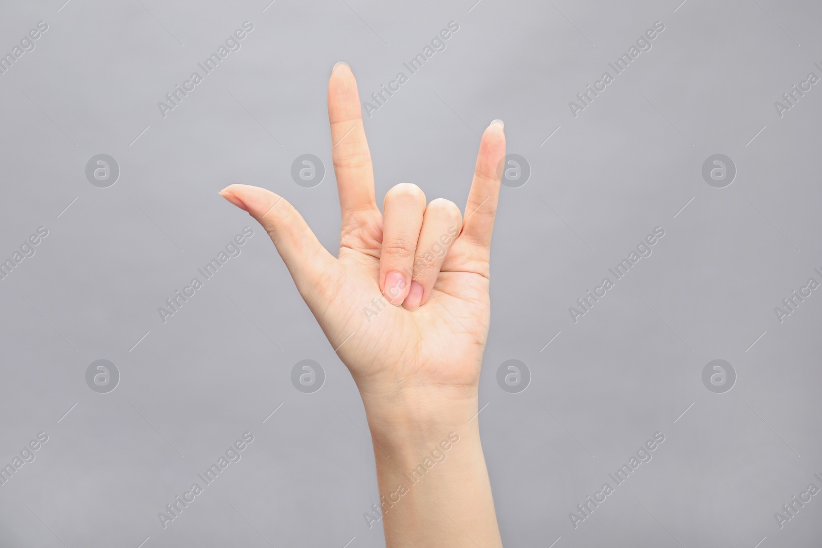 Photo of Woman showing hand sign on grey background, closeup. Body language