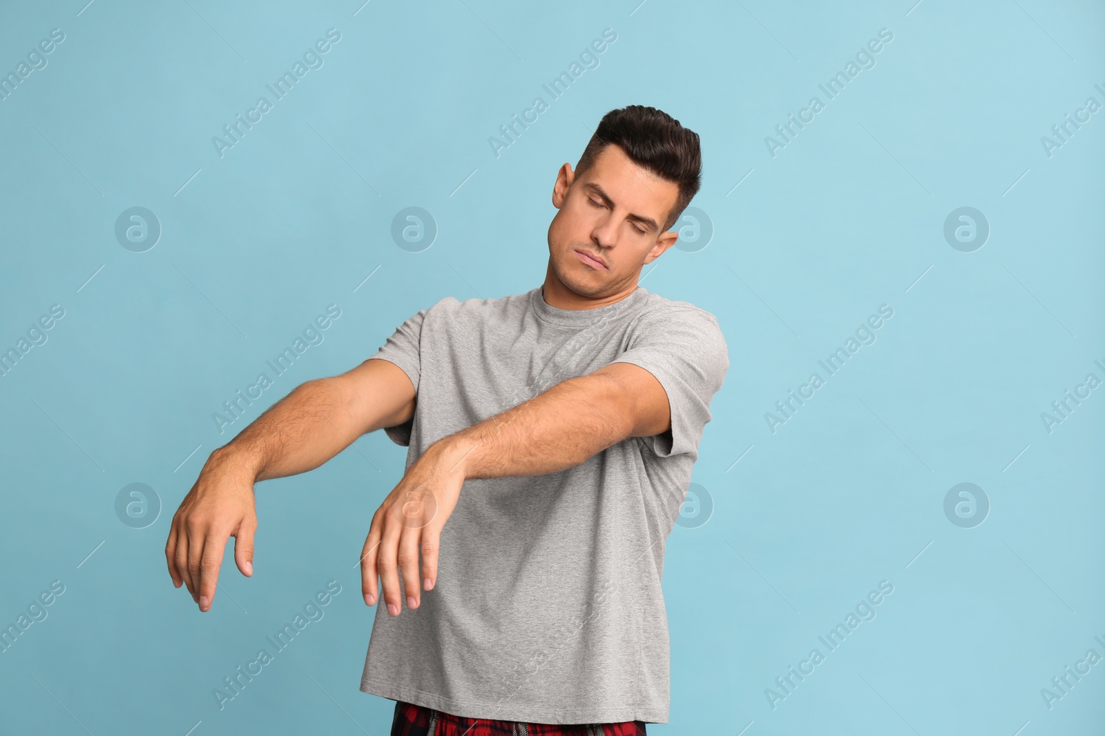 Photo of Somnambulist in pajamas on light blue background. Sleepwalking