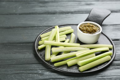 Slate board with celery sticks and dip sauce on grey wooden table