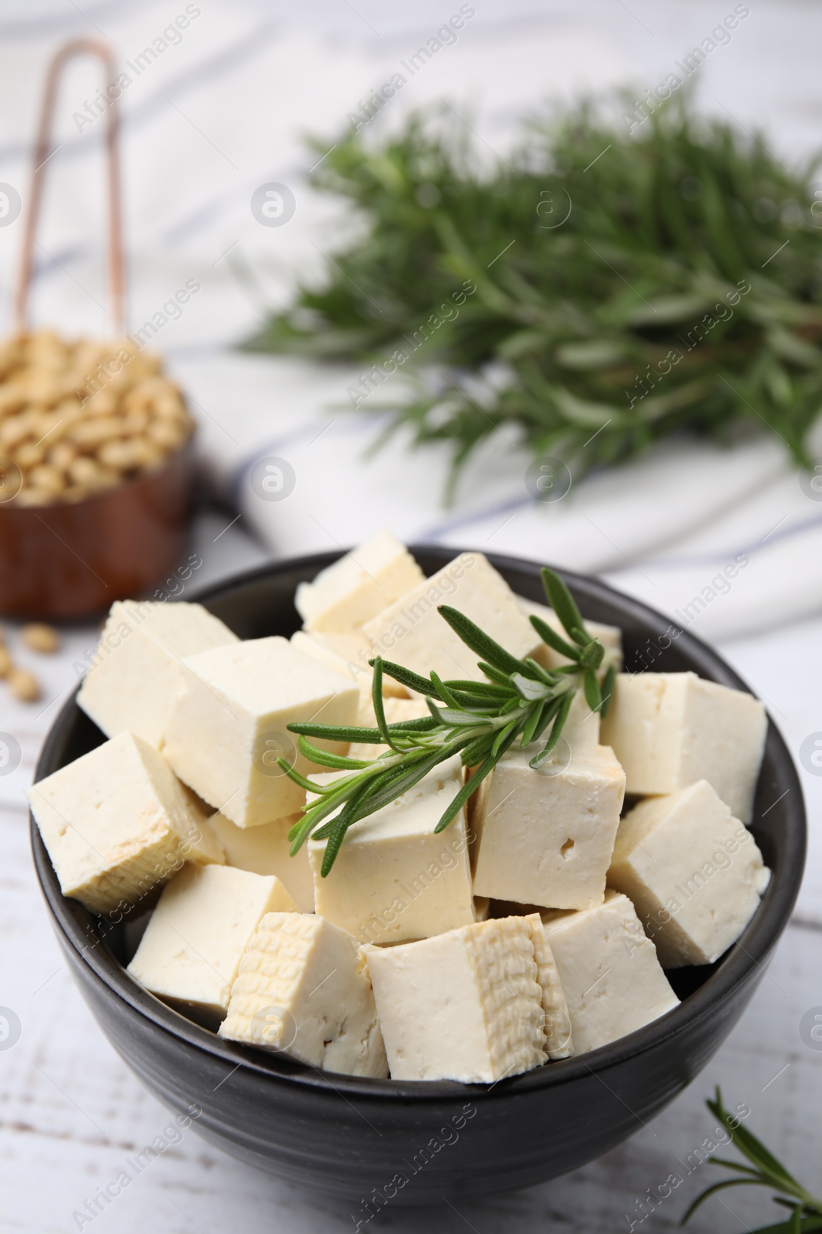 Photo of Delicious tofu cheese, rosemary and soybeans on white wooden table, closeup