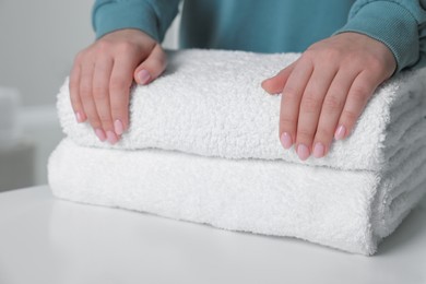 Woman touching soft white towel indoors, closeup