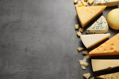 Photo of Different delicious cheeses on grey table, top view. Space for text