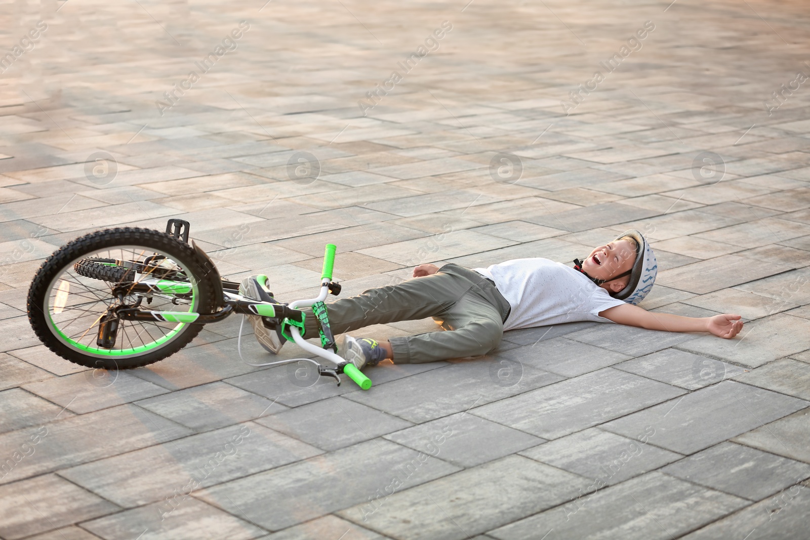 Photo of Little boy fallen off his bicycle on street