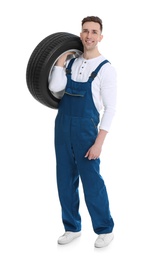 Male mechanic with car tire on white background