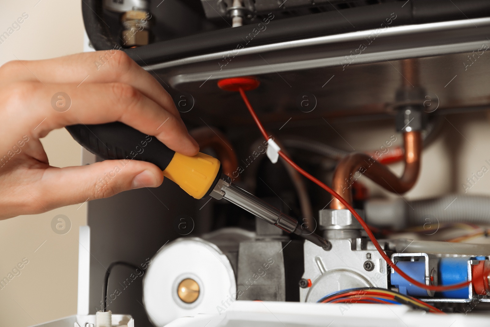 Photo of Man repairing gas boiler with screwdriver, closeup