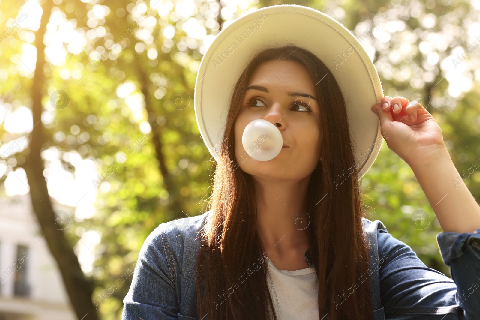 Photo of Beautiful young woman blowing chewing gum outdoors