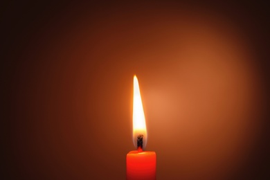 Photo of Wax candle burning in darkness, closeup