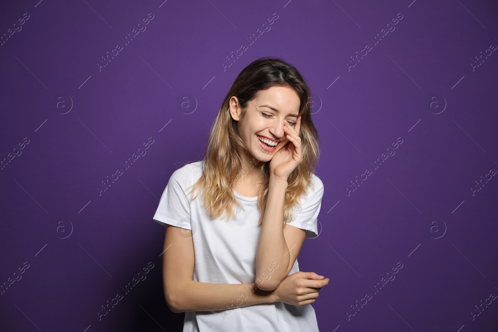 Photo of Cheerful young woman laughing on violet background