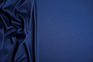 Crumpled dark blue silk fabric as background, top view. Space for text