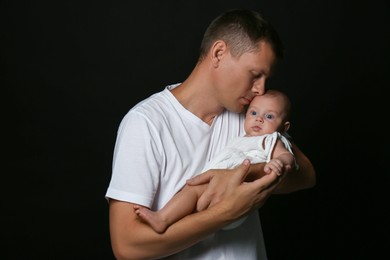 Photo of Happy father with his little baby on black background