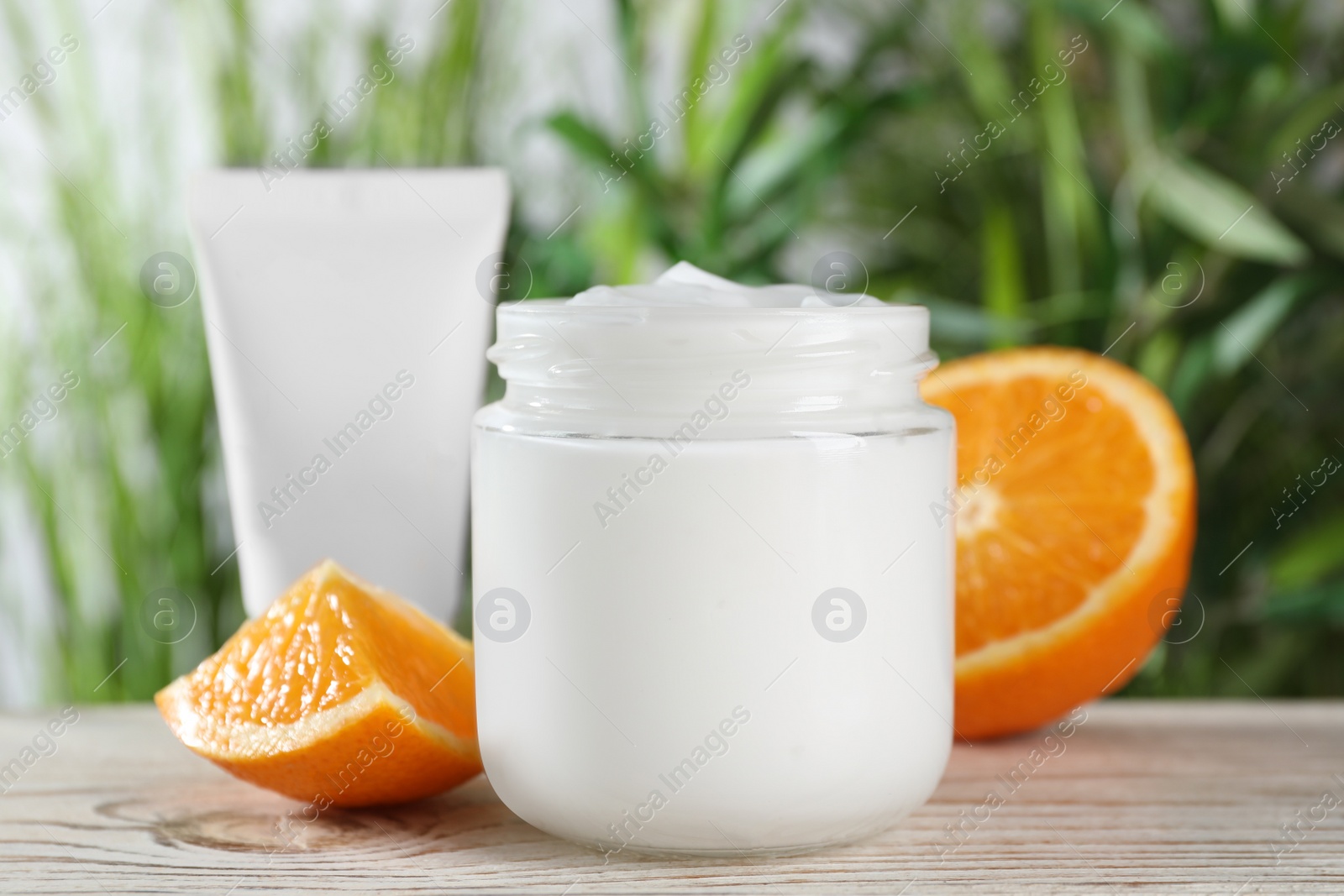 Photo of Jar of hand cream and orange on white wooden table