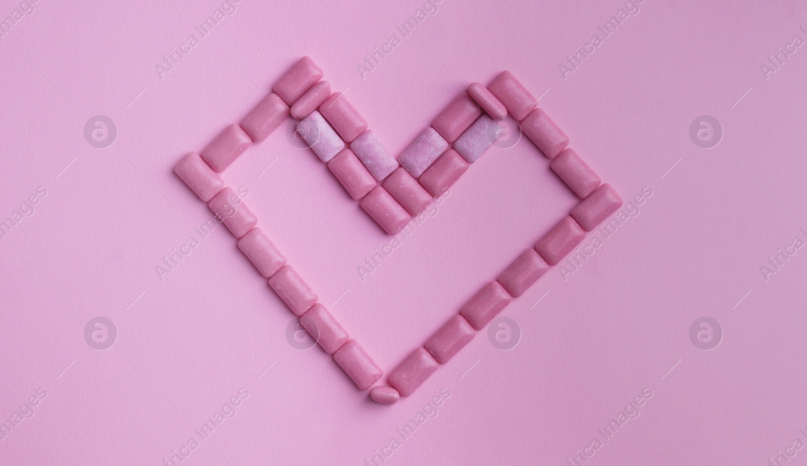 Photo of Heart made of sweet chewing gums on pink background, top view