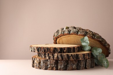 Photo of Presentation for product. Wooden stumps and eucalyptus branches on beige background. Space for text