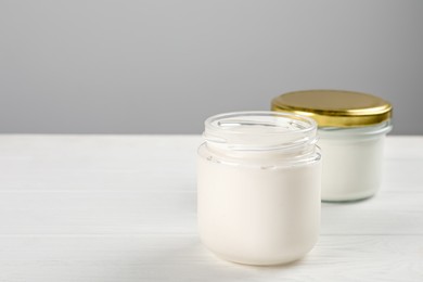 Jars with delicious organic yogurt on white wooden table, closeup. Space for text