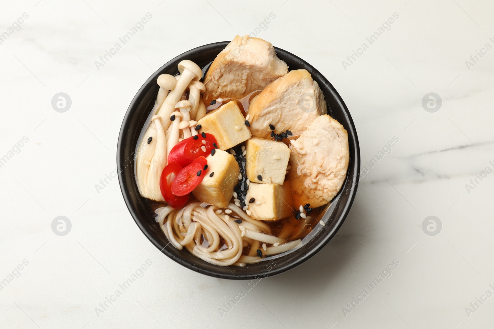 Photo of Bowl of delicious ramen on white marble table, top view. Noodle soup