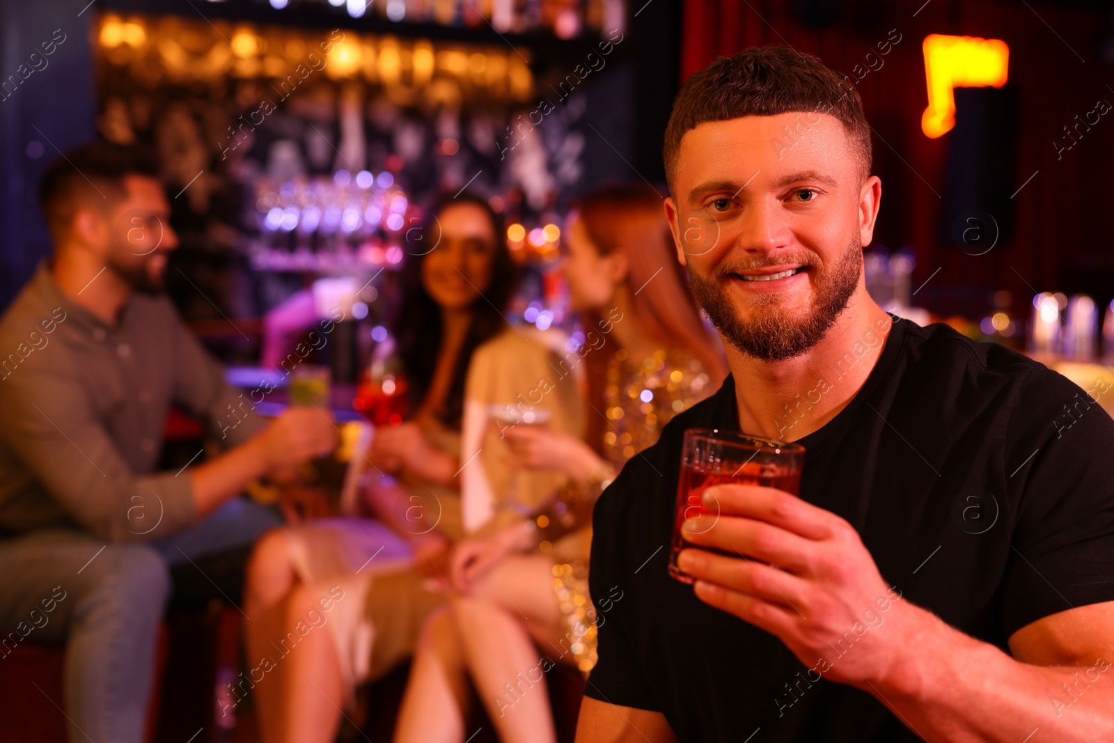 Photo of Friends spending time together in bar. Handsome man with fresh alcoholic cocktail, space for text