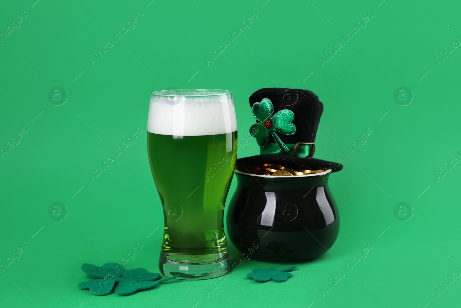 Photo of St. Patrick's day party. Green beer, leprechaun hat, pot of gold and decorative clover leaves on green background