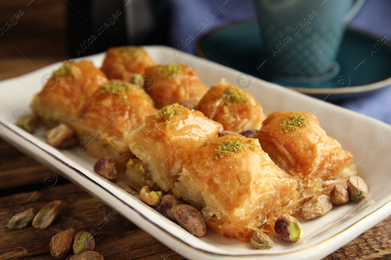 Photo of Delicious baklava with pistachios and scattered nuts on wooden table, closeup