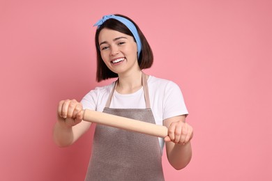 Photo of Happy confectioner with rolling pin on pink background