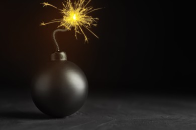 Image of Old fashioned black bomb with lit fuse on grey table, space for text