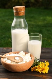 Photo of Tasty fresh milk and cottage cheese on wooden table outdoors