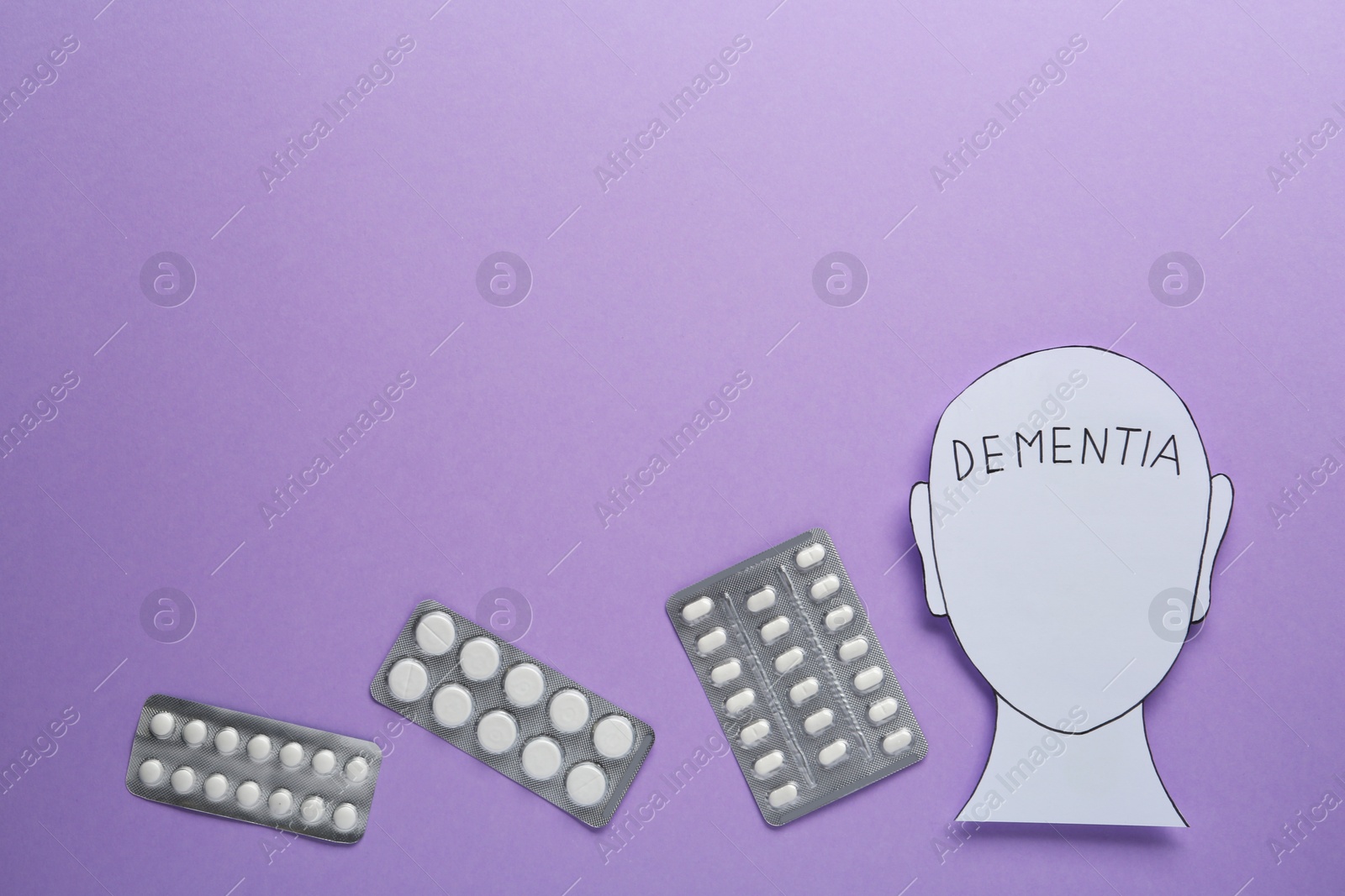 Photo of Human head paper cutout with word Dementia and pills on violet background, flat lay. Space for text