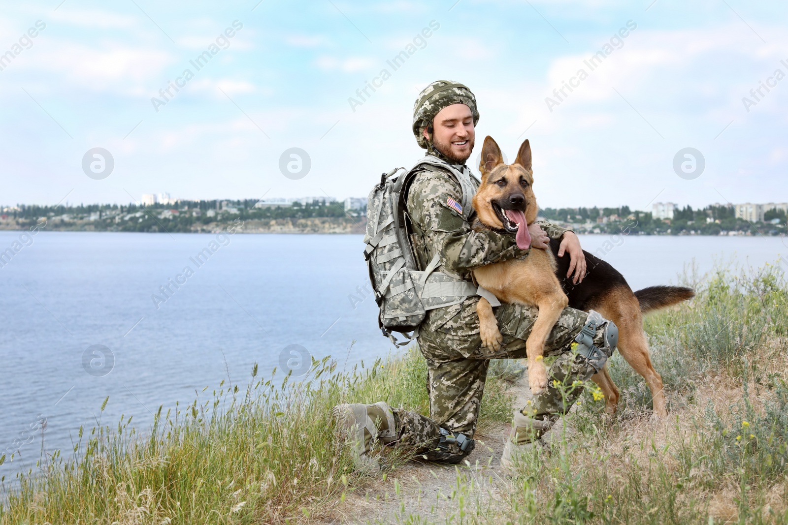 Photo of Man in military uniform with German shepherd dog outdoors