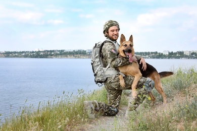 Man in military uniform with German shepherd dog outdoors