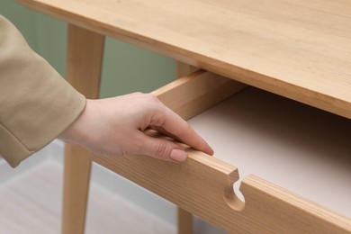 Woman opening empty desk drawer indoors, closeup view