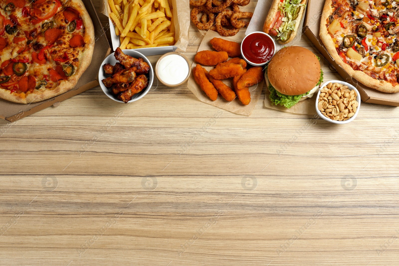 Photo of French fries, pizza and other fast food on wooden table, flat lay with space for text