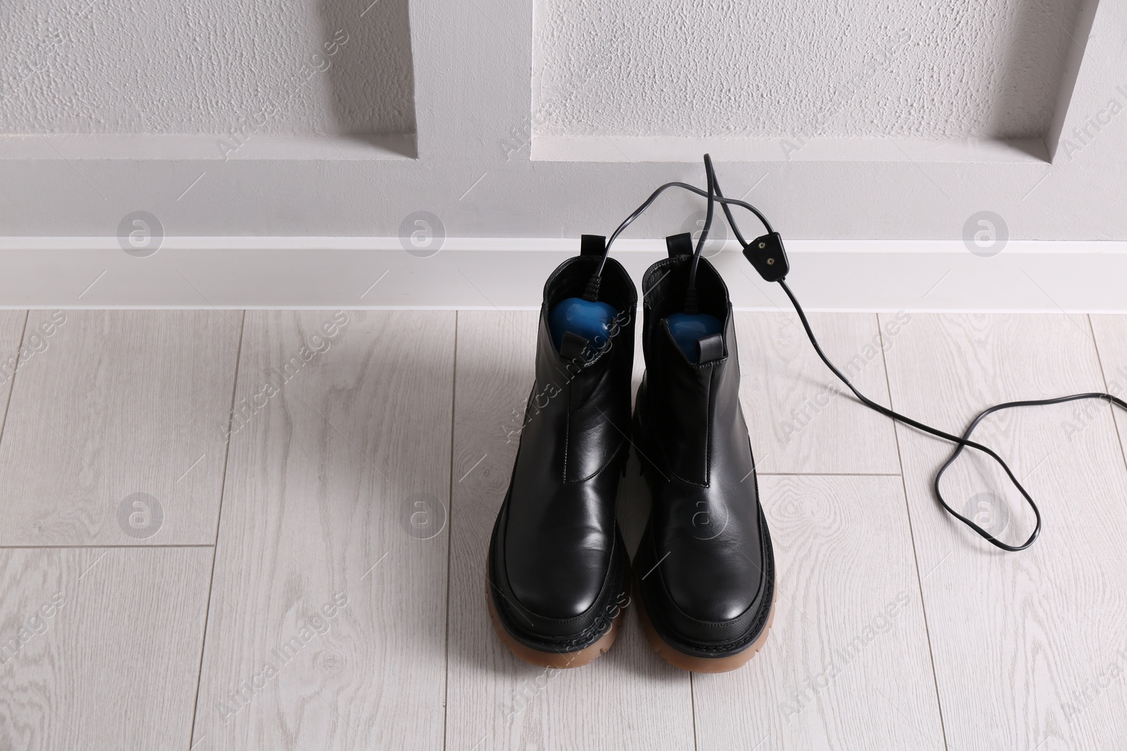 Photo of Shoes with electric dryer on floor indoors, space for text