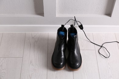 Shoes with electric dryer on floor indoors, space for text