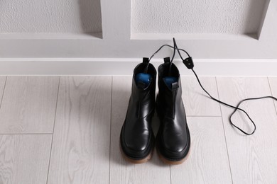 Photo of Shoes with electric dryer on floor indoors, space for text