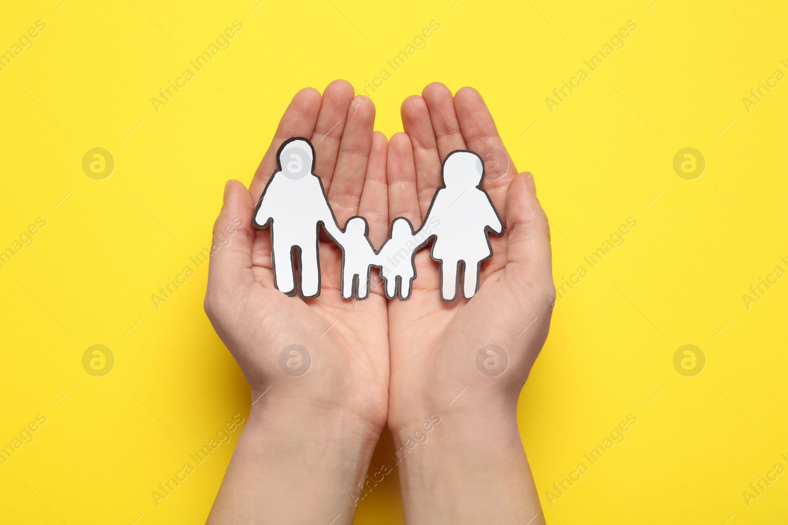 Photo of Woman holding paper family cutout on yellow  background, top view