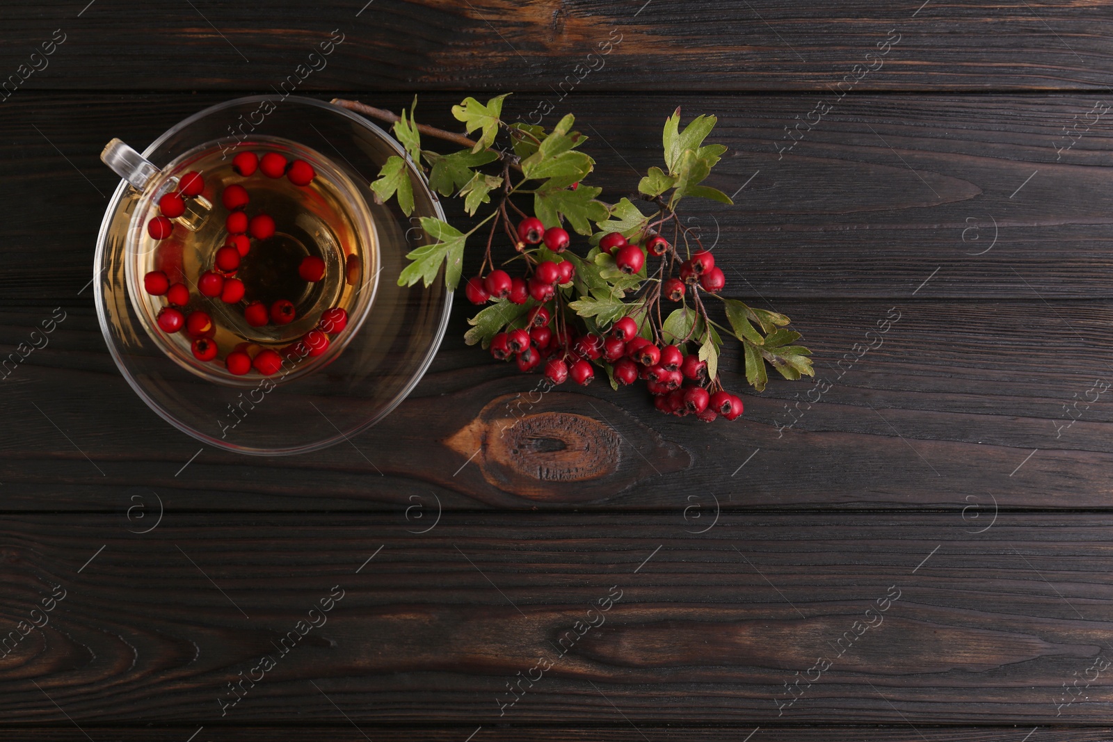 Photo of Cup of delicious immunity boosting tea with hawthorn on wooden table, flat lay. Space for text