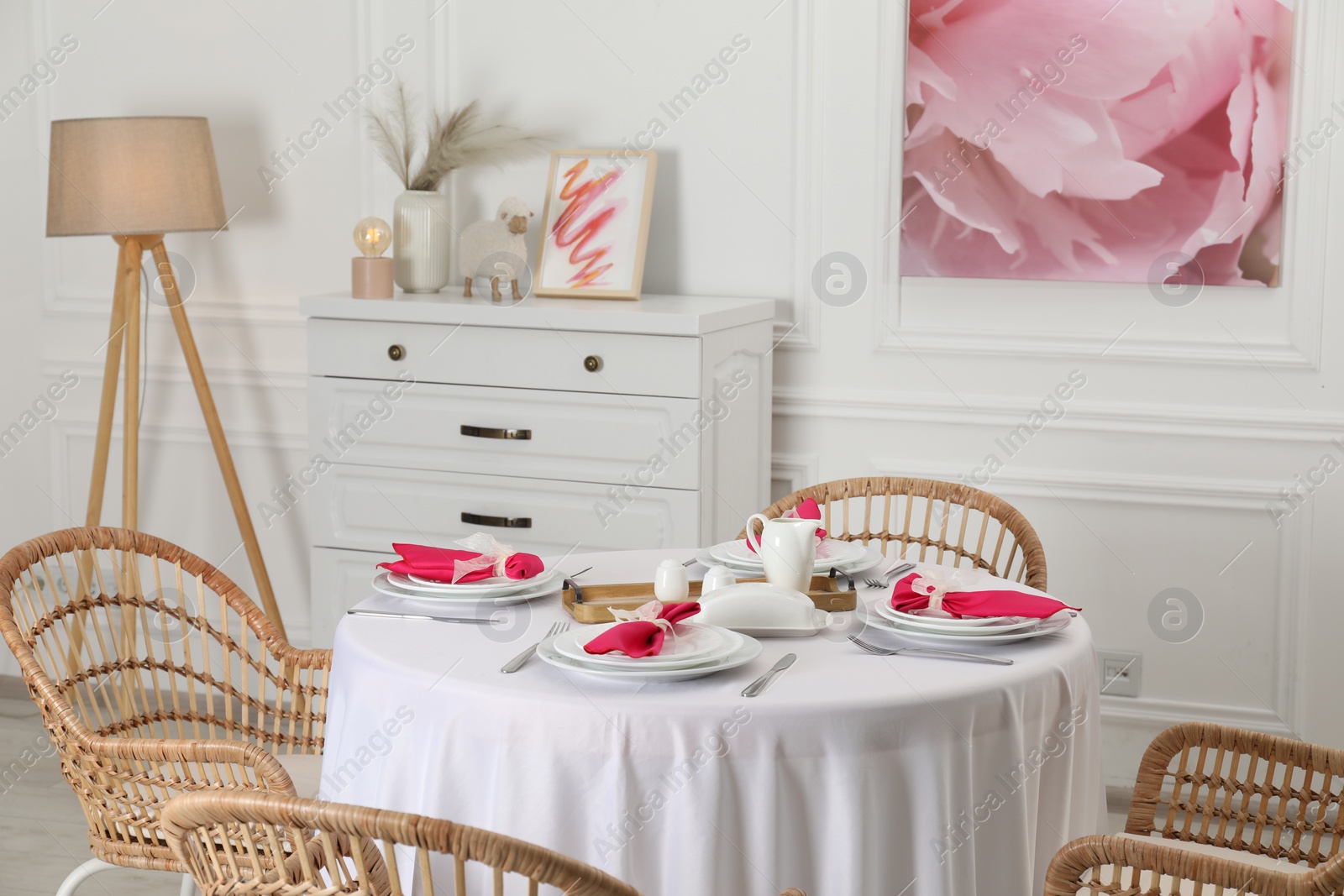 Photo of Color accent table setting. Plates, cutlery and pink napkins in dining room