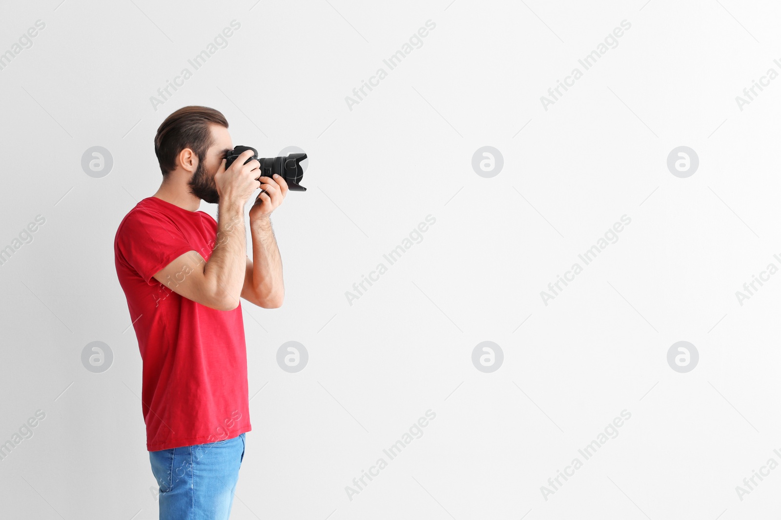 Photo of Young photographer with professional camera on white background