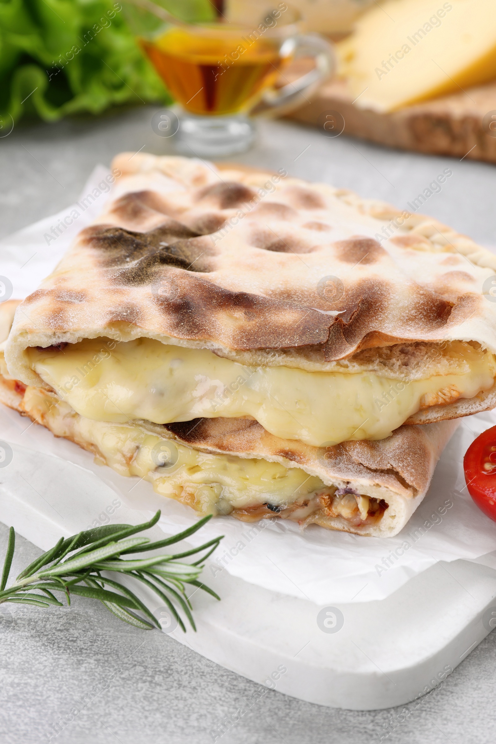 Photo of Tasty pizza calzones with cheese and rosemary on light grey table, closeup