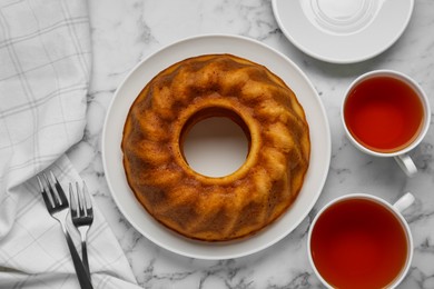 Photo of Homemade yogurt cake and aromatic tea on white marble table, flat lay