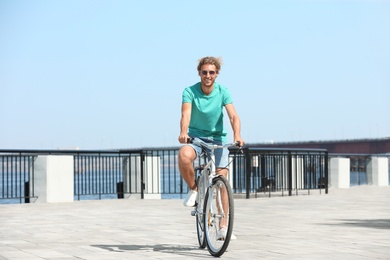 Photo of Handsome young man riding bicycle outdoors on sunny day