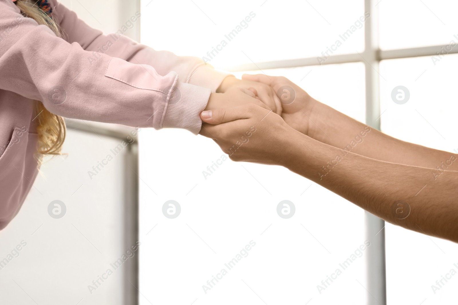 Photo of Mother holding hands with her child indoors, closeup. Happy family